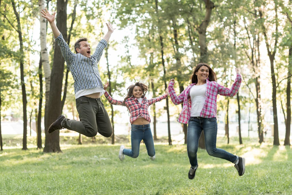 Happy family jumping in green nature <a href='https://www.freepik.com/photos/tree'>Tree photo created by freepik - www.freepik.com</a>