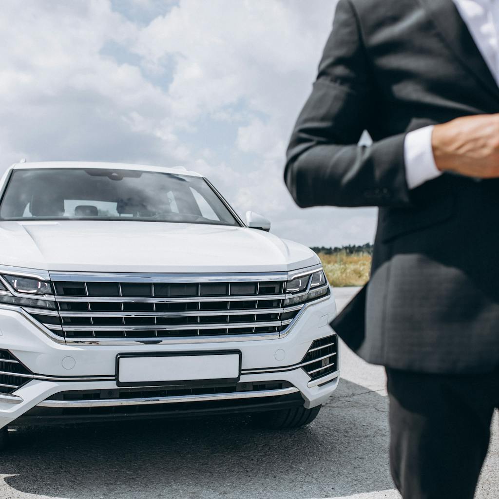 Business man standing by a big luxurious white car <a href='https://www.freepik.com/photos/business'>Business photo created by senivpetro - www.freepik.com</a>