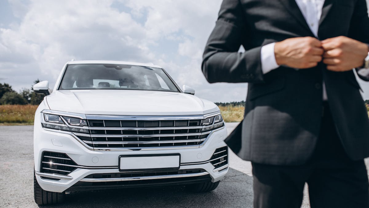 Business man standing by a big luxurious white car <a href='https://www.freepik.com/photos/business'>Business photo created by senivpetro - www.freepik.com</a>
