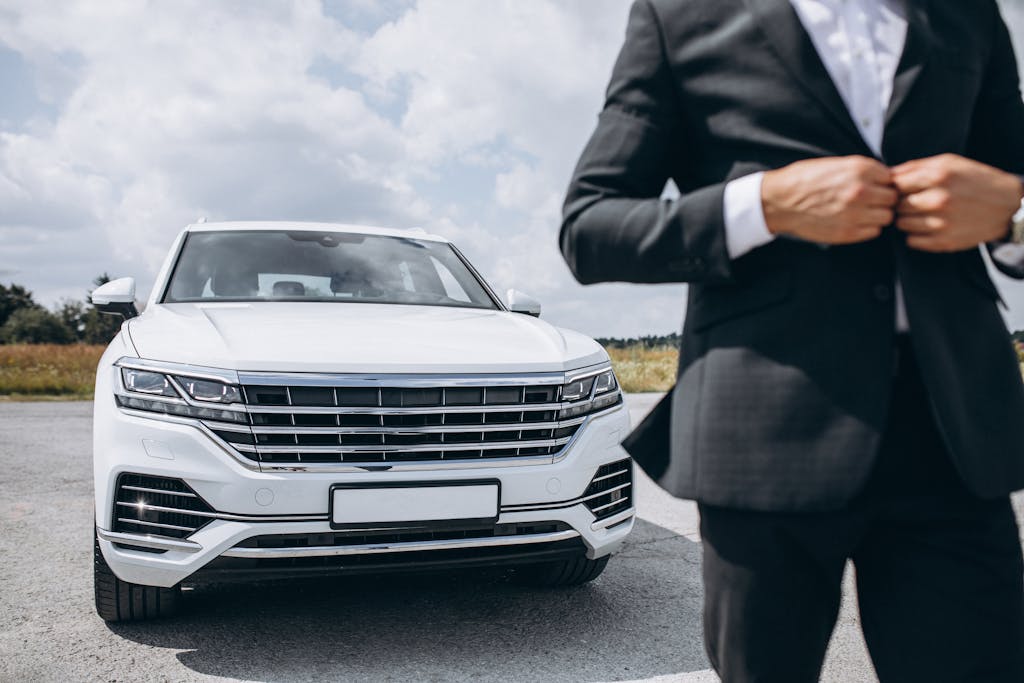 Business man standing by a big luxurious white car <a href='https://www.freepik.com/photos/business'>Business photo created by senivpetro - www.freepik.com</a>