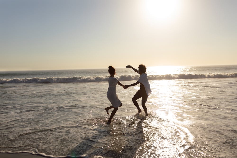 Photo of a couple having fun while dancing together on the beach <a href="https://www.freepik.com/free-photo/couple-having-fun-while-taking-selfie-with-mobile-phone-beach_5195151.htm#query=free%20happy%20beach&position=18&from_view=search&track=ais">Image by wavebreakmedia_micro</a> on Freepik