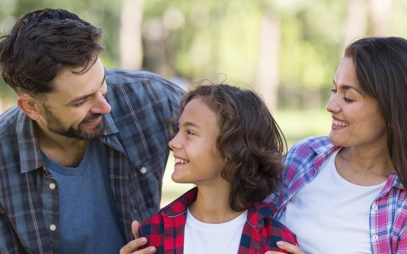 Niño sonriendo mientras sus padres lo abrazan