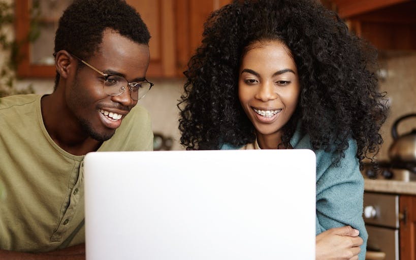 A couple looking at the laptop smiling