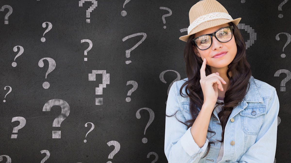 Woman in front of a black board with questions marks