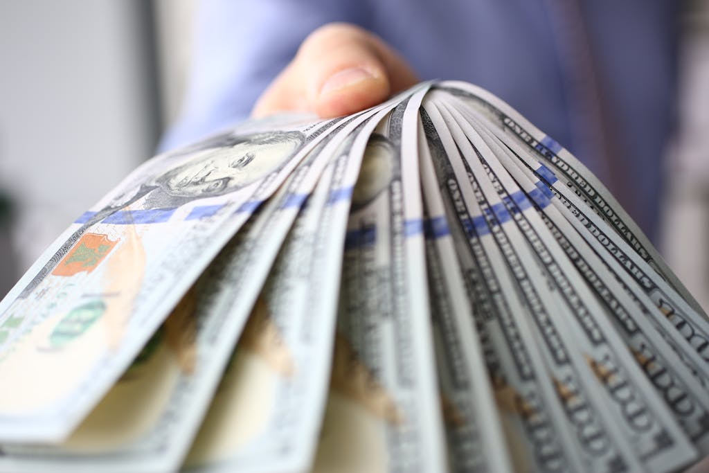 Man in suit and tie hold in arm pack of hundred of dollars
