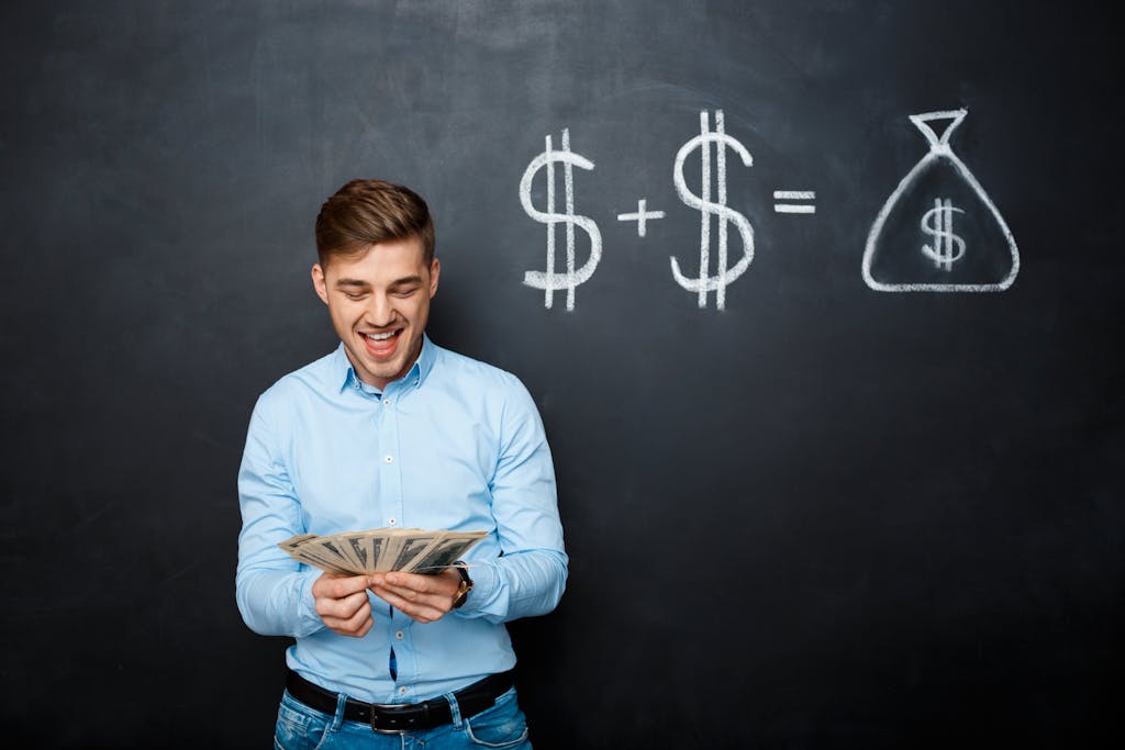 Man holding several bills of U.S. dollars standing over a blackboard with drawn dollar signs 