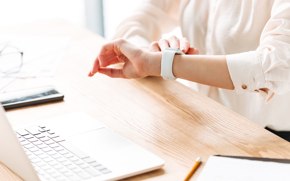 Woman sit down on a desk looking at her watch