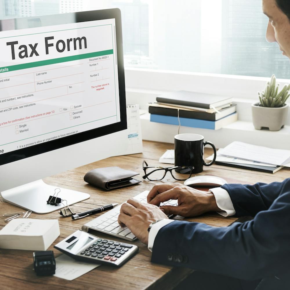 Young man sitting on his desk working on his computer filling out his tax form <a href="https://www.freepik.com/free-photo/tax-credits-claim-return-deduction-refund-concept_16470144.htm#query=taxes&position=49&from_view=search&track=sph">Image by rawpixel.com</a> on Freepik