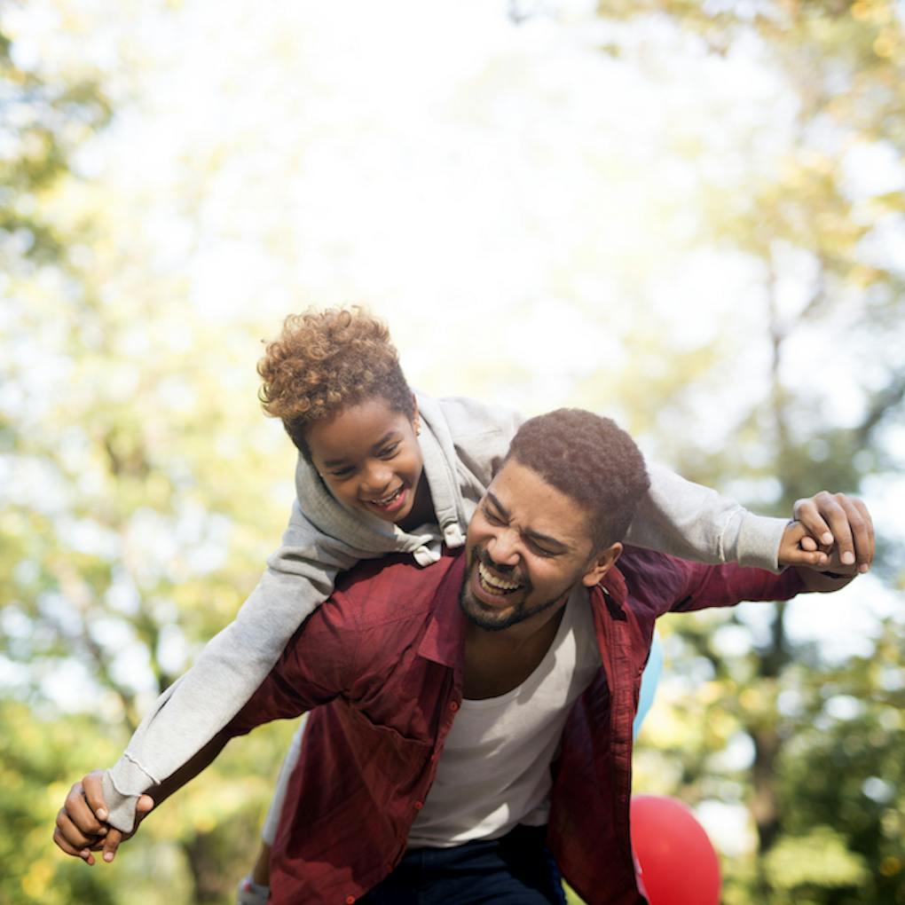 Padre sosteniendo a su hija sobre los hombros y riendo