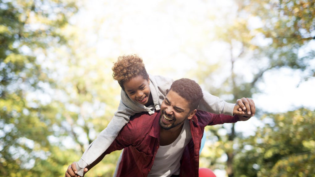 Padre sosteniendo a su hija sobre los hombros y riendo