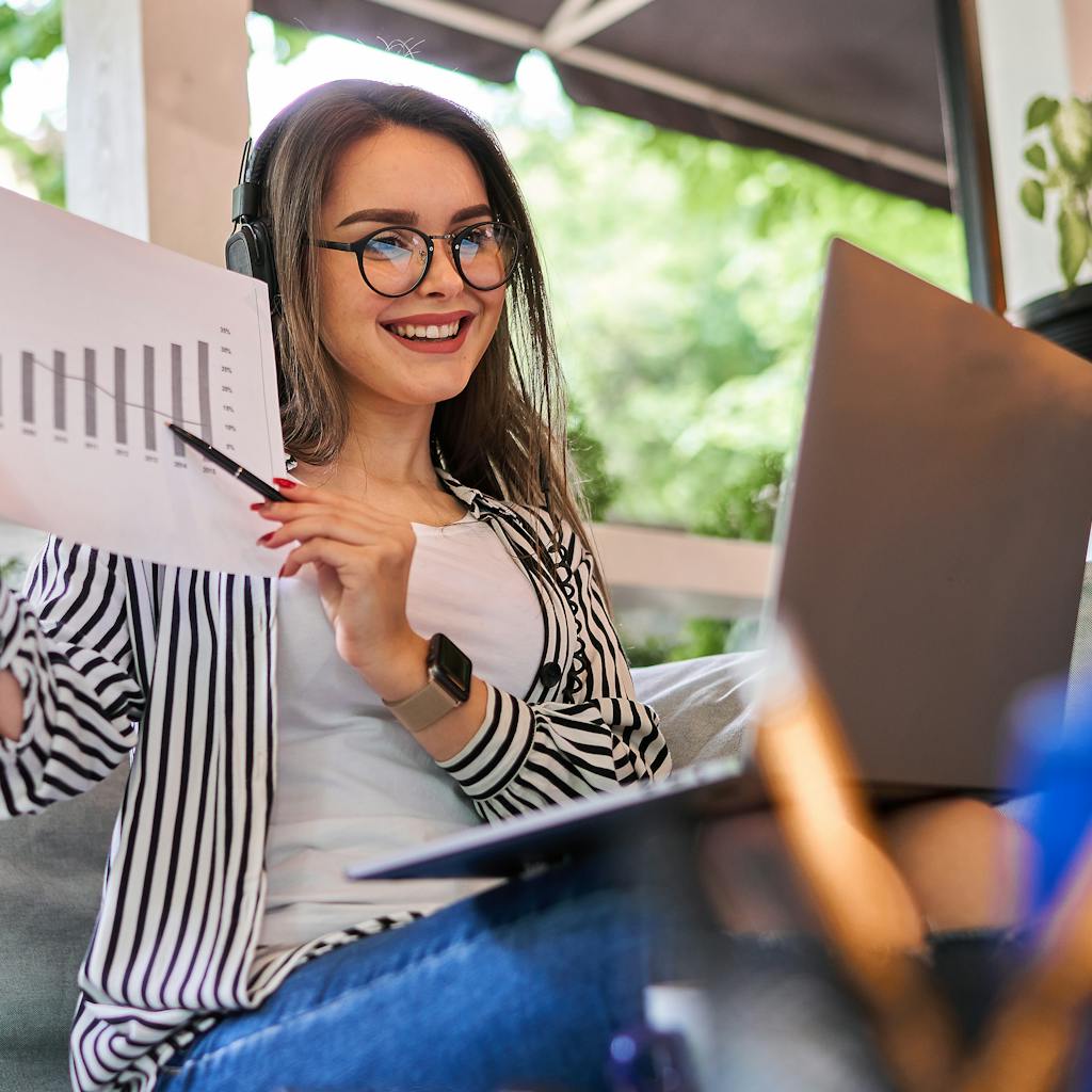 Young investor woman shows a graphic while smiling and working on her investments at home