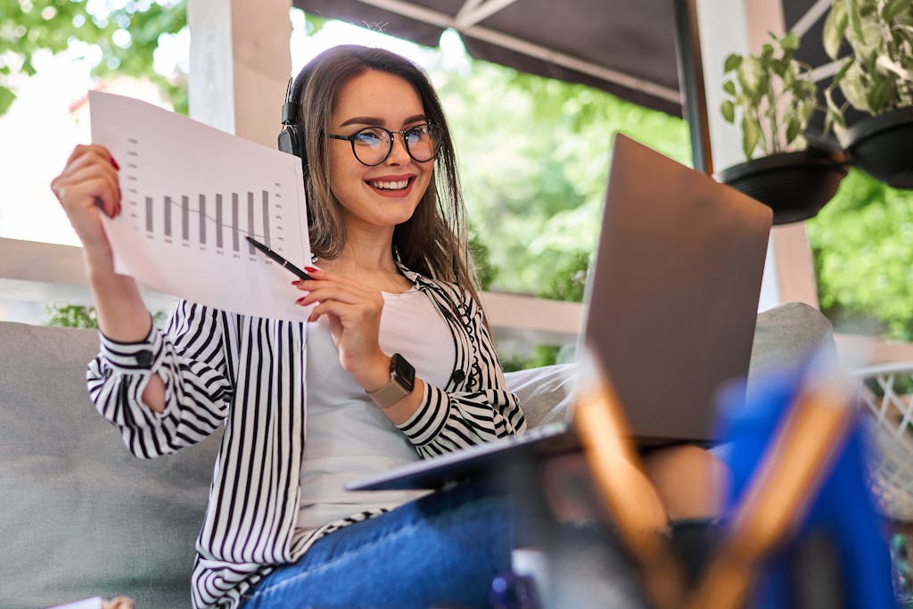 Young investor woman shows a graphic while smiling and working on her investments at home