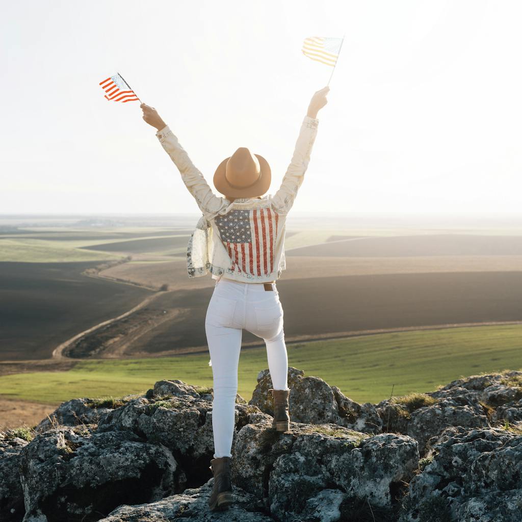 Patriotic woman posing with American flags on top of mountain