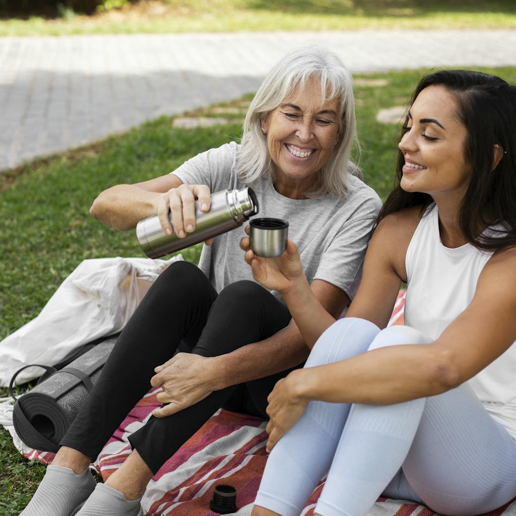 Older and younger friends doing yoga together in park