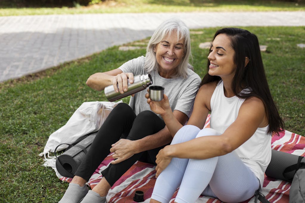 Older and younger friends doing yoga together in park