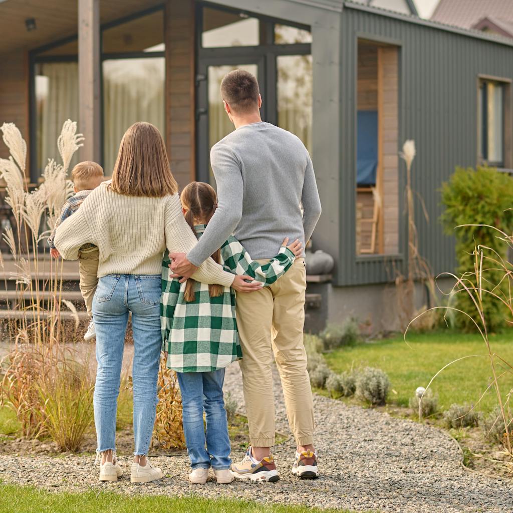 Back view of family hugging and admiring their home
