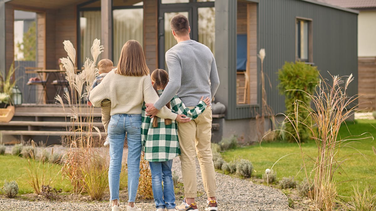 Back view of family hugging and admiring their home