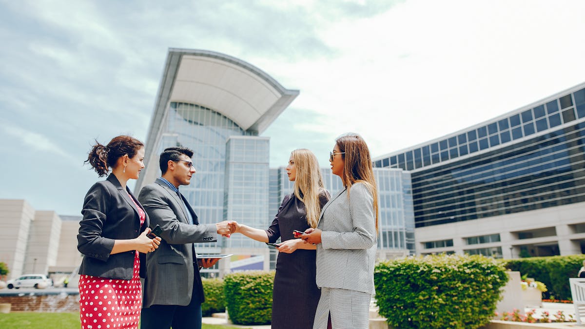 A businessman with  three businesswomen in a city during the summer
