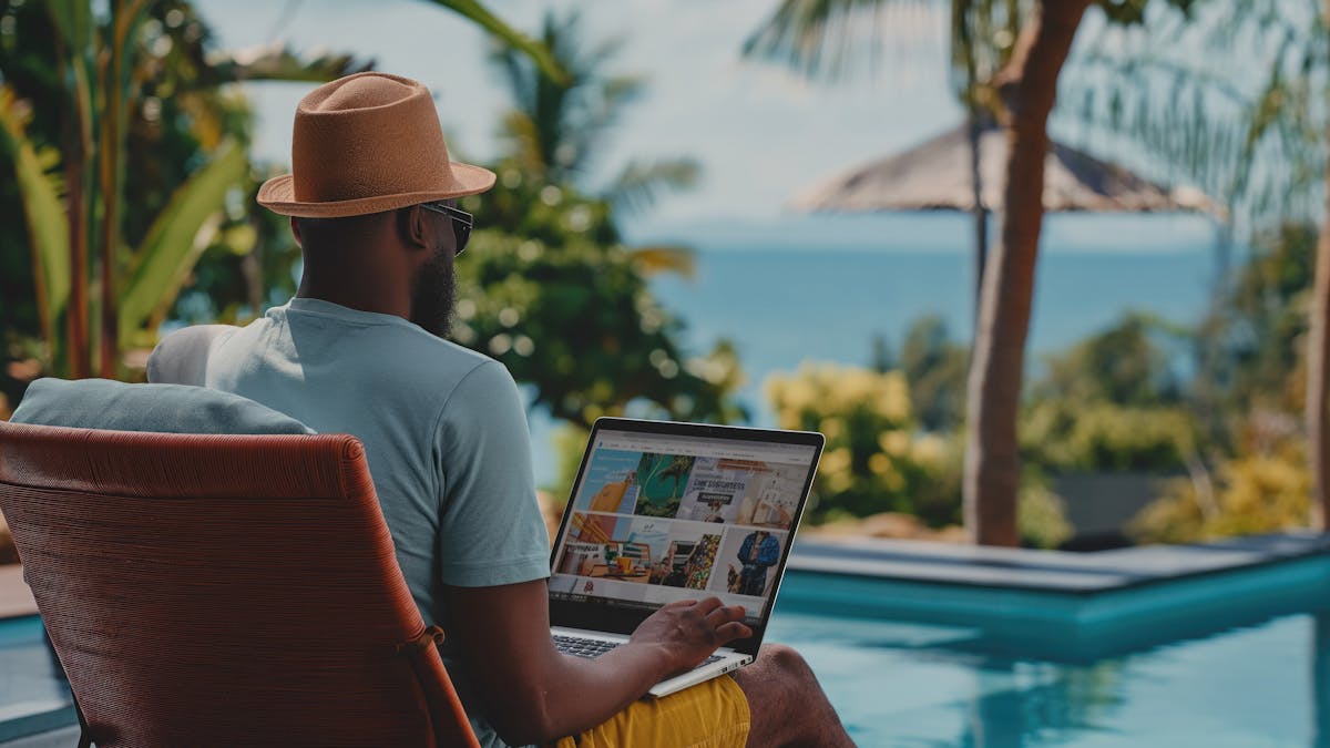 Hombre trabajando en su portátil con vistas a la piscina y al océano