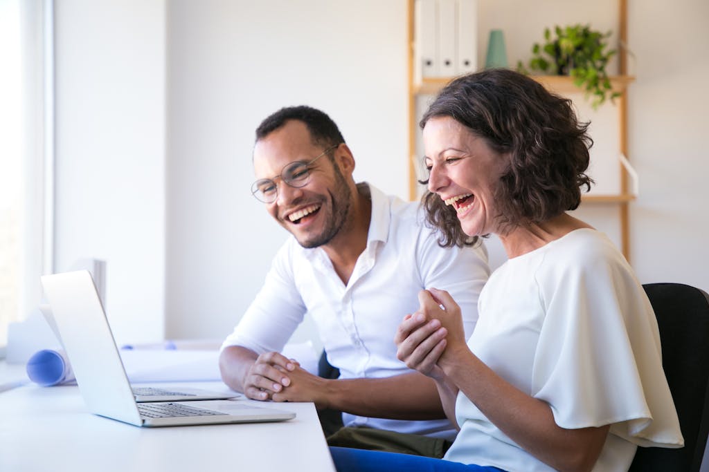 Pareja feliz se ríe mientras leen frente a su computadora