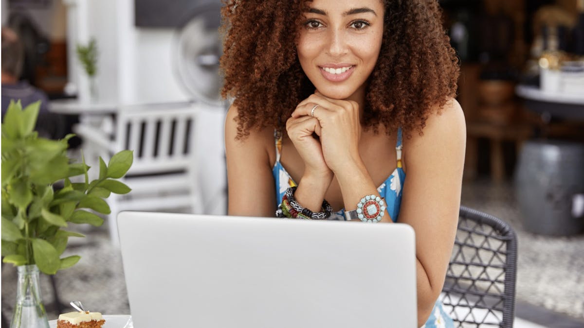 Woman smiles while working on her computer in a pretty cafe