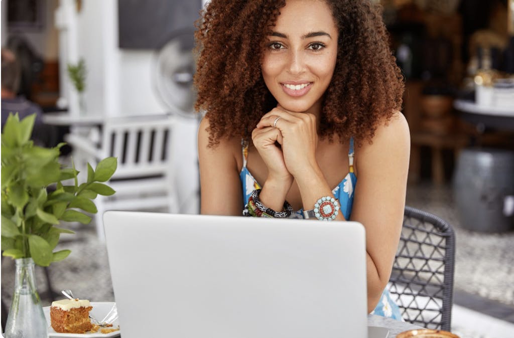Woman smiles while working on her computer in a pretty cafe