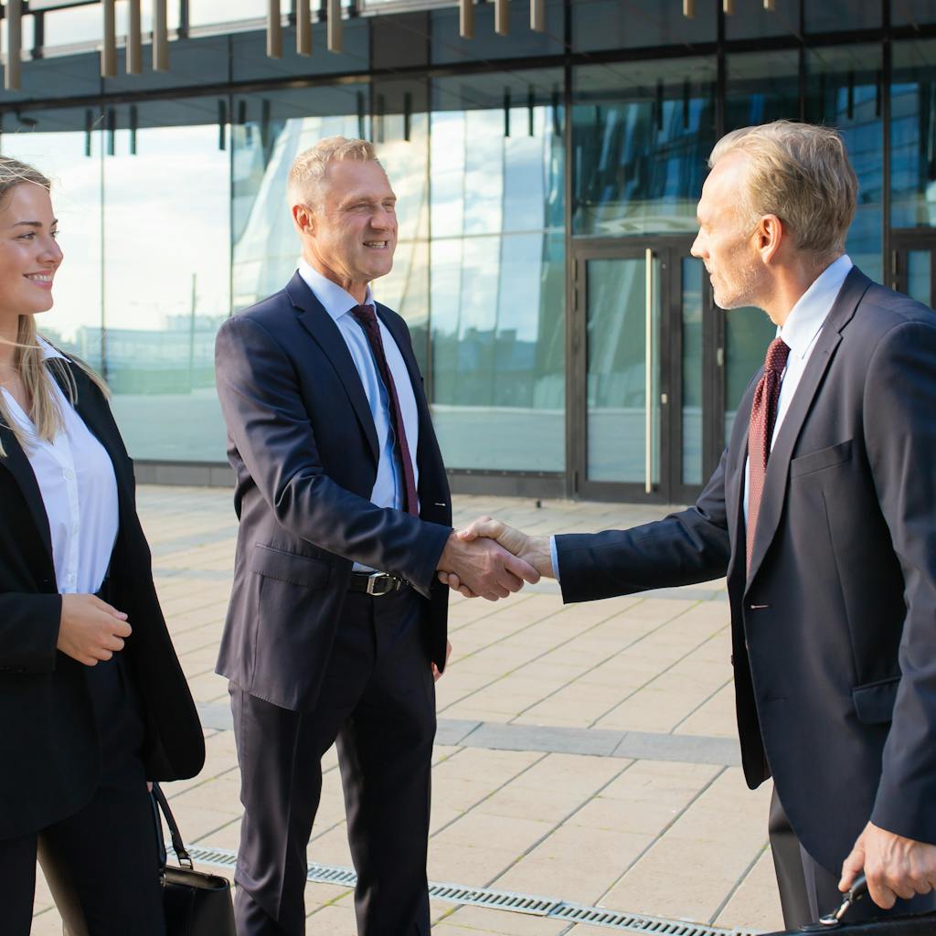 Partners meeting at office building, shaking hands and smiling