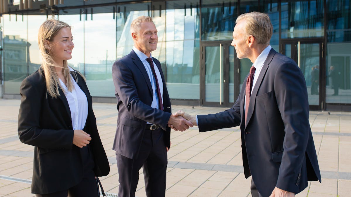 Partners meeting at office building, shaking hands and smiling