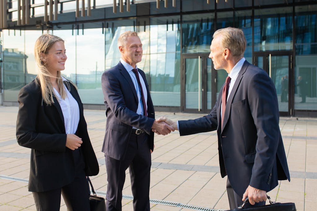 Partners meeting at office building, shaking hands and smiling