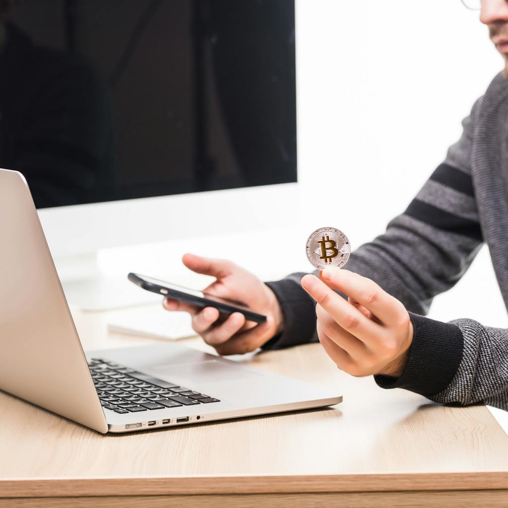 close-up-hands-man-working-place-woth-laptop-monitor-screen-holding-phone-bitcoin