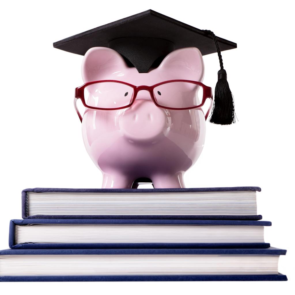 Piggybank wearing a graduate hat standing on top of three big books <a href="https://www.freepik.com/photos/background">Background photo created by kstudio - www.freepik.com</a>