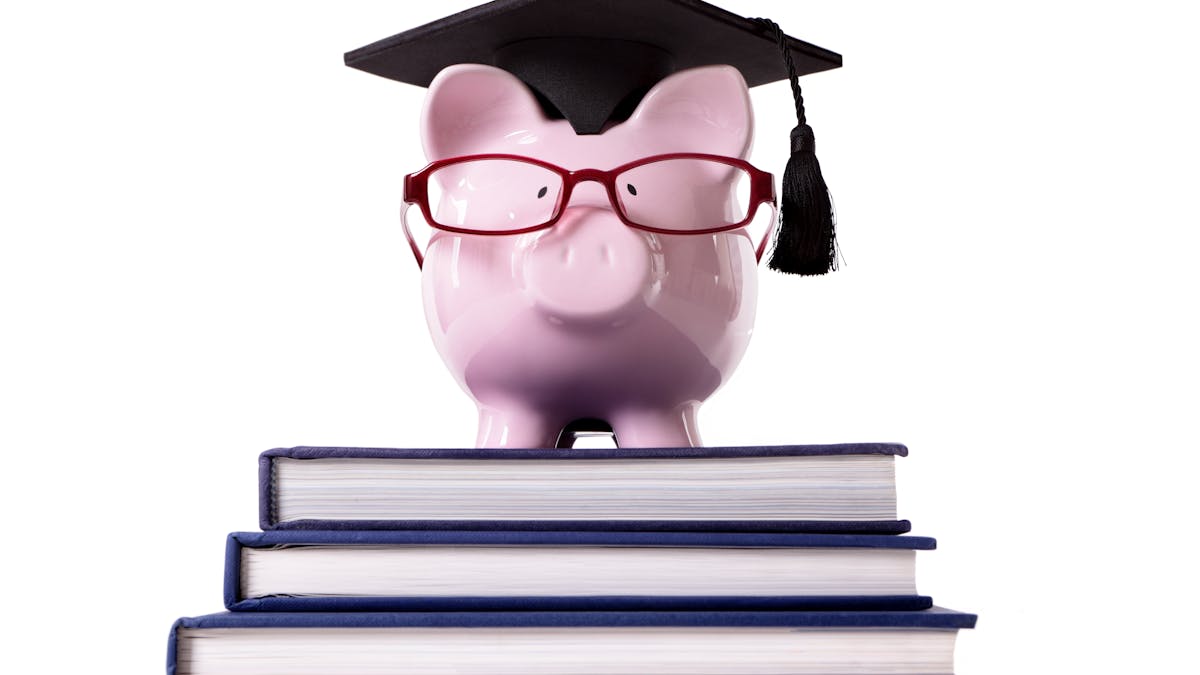 Piggybank wearing a graduate hat standing on top of three big books <a href="https://www.freepik.com/photos/background">Background photo created by kstudio - www.freepik.com</a>