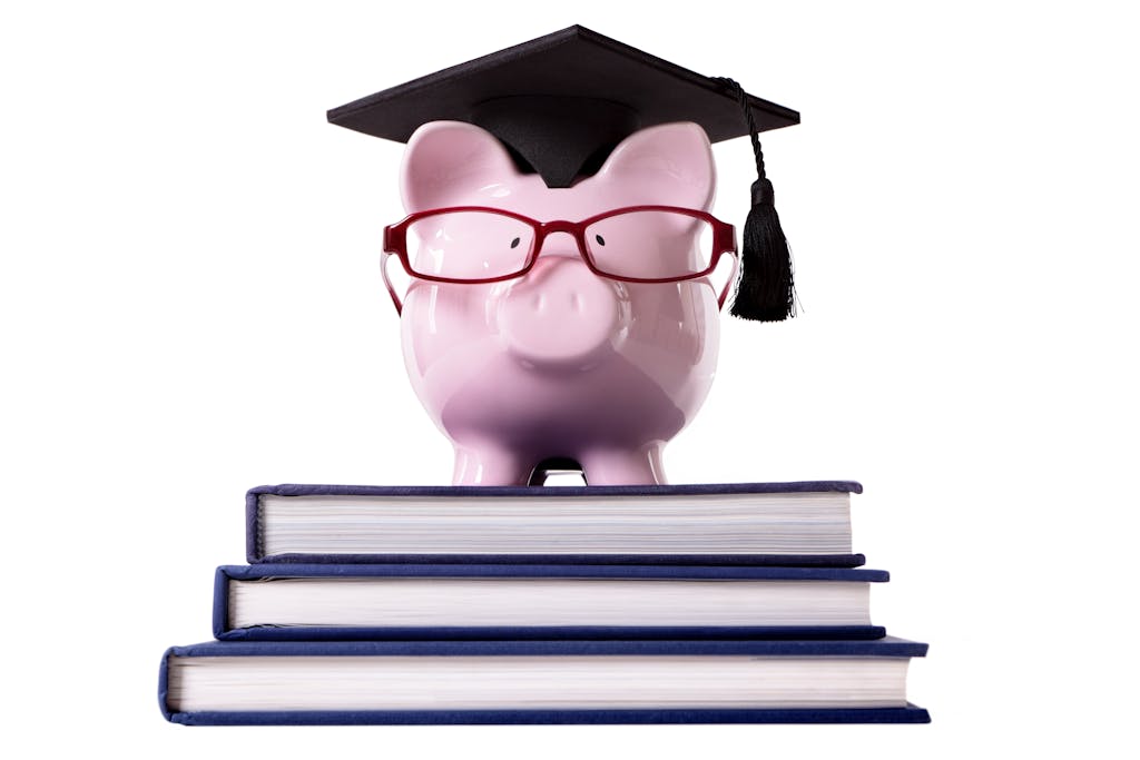 Piggybank wearing a graduate hat standing on top of three big books <a href="https://www.freepik.com/photos/background">Background photo created by kstudio - www.freepik.com</a>