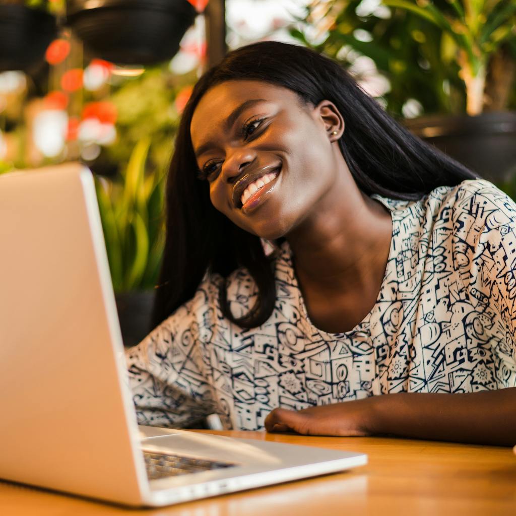 Young african woman siting at cafe smiling and working on laptop <a href="https://www.freepik.com/photos/coffee">Coffee photo created by diana.grytsku - www.freepik.com</a>