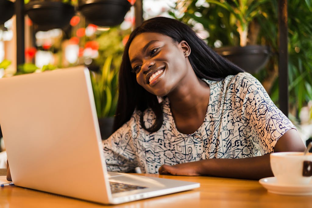 Young african woman siting at cafe smiling and working on laptop <a href="https://www.freepik.com/photos/coffee">Coffee photo created by diana.grytsku - www.freepik.com</a>