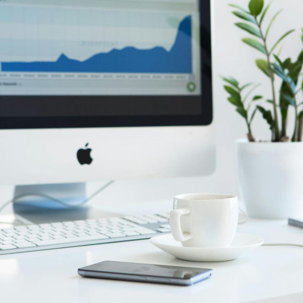 Desktop with keyboard, monitor, teacup, plant and hourglass