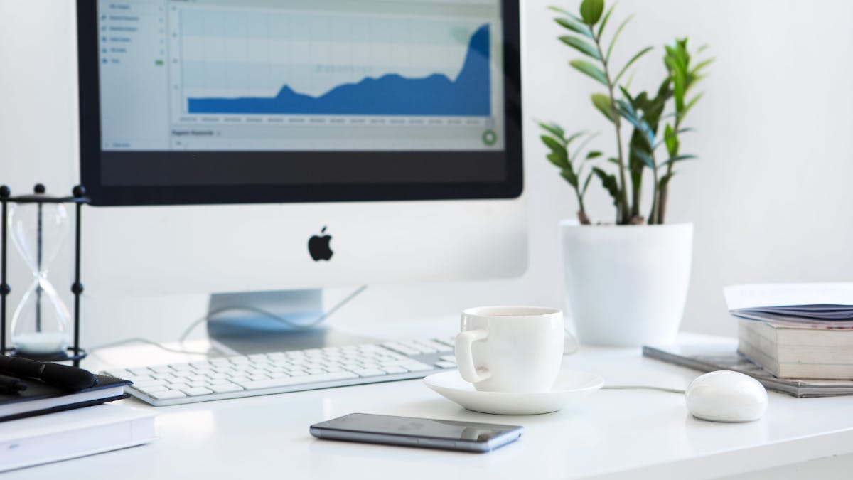 Desktop with keyboard, monitor, teacup, plant and hourglass