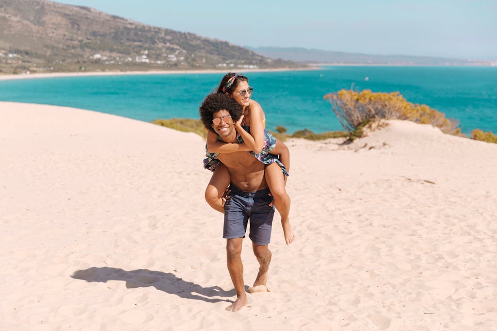 Young man carrying young woman on his back as they enjoy the beach