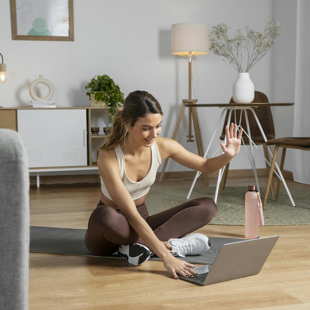 Una monitora de fitness utiliza un ordenador portátil para impartir una clase desde casa- Imagen por <a href="https://www.freepik.com/free-photo/female-fitness-instructor-using-laptop-teach-class-from-home_23674959.htm#query=working%20from%20home&position=28&from_view=search">Freepik</a>