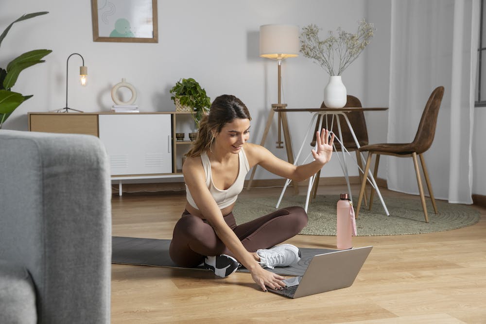 Female fitness instructor using laptop to teach a class from home- Image by <a href="https://www.freepik.com/free-photo/female-fitness-instructor-using-laptop-teach-class-from-home_23674959.htm#query=working%20from%20home&position=28&from_view=search">Freepik</a>