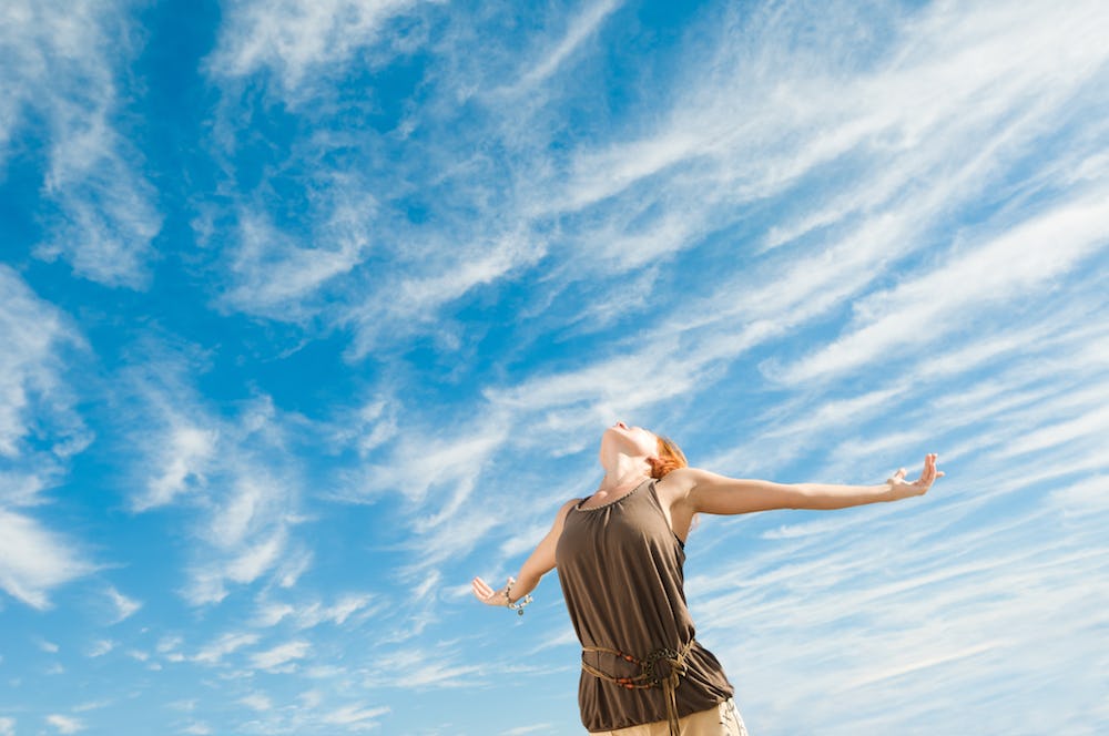 Woman with open arms looking at the blue sky