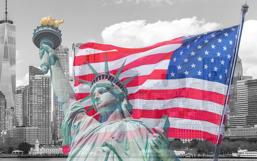 Estatua de la Libertad con Bandera Estadounidense y edificios de fondo