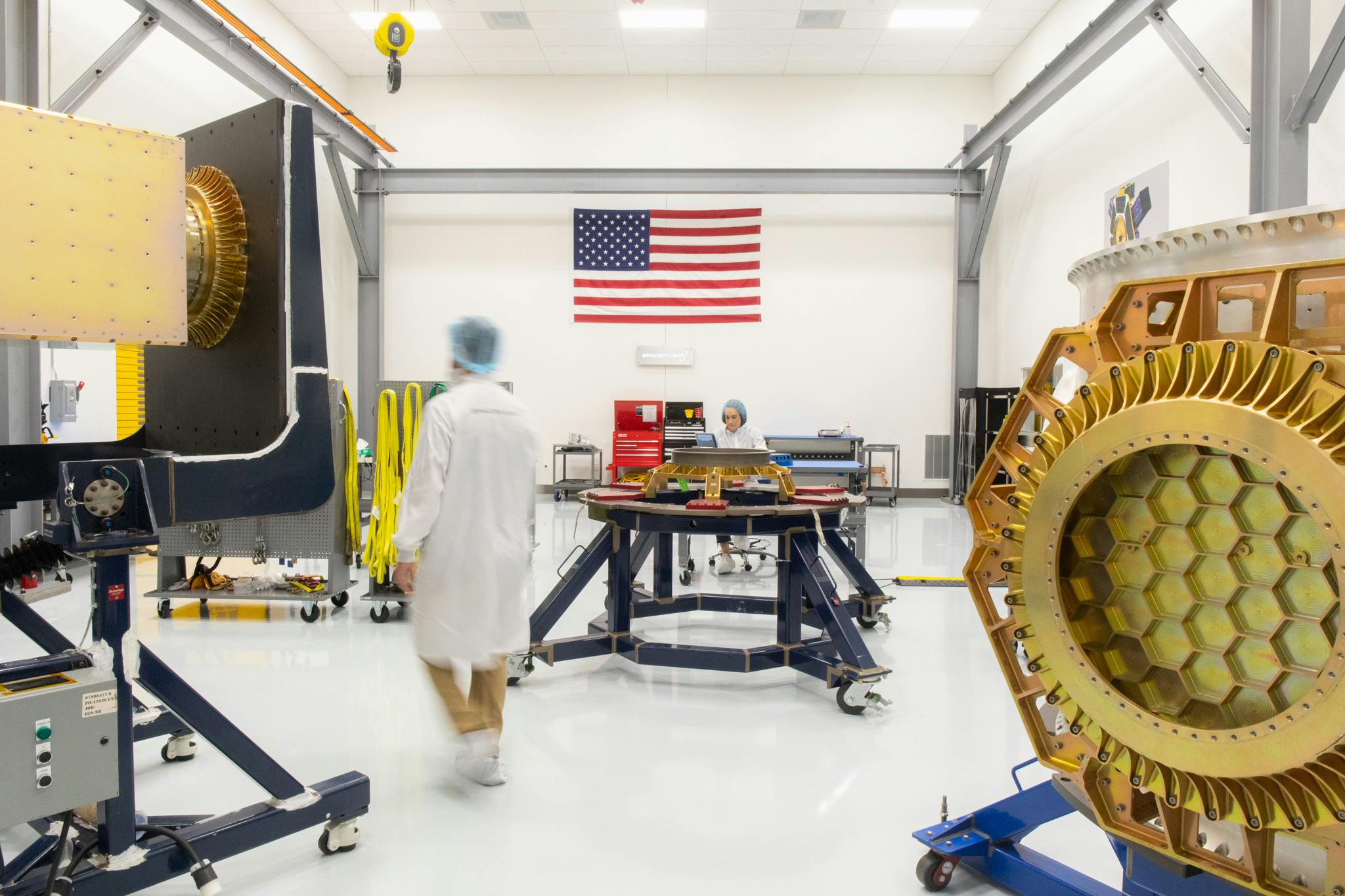 Inside Spaceflight's cleanroom. A large piece of equipment is in the foreground, while two people in lab coats work in the background.