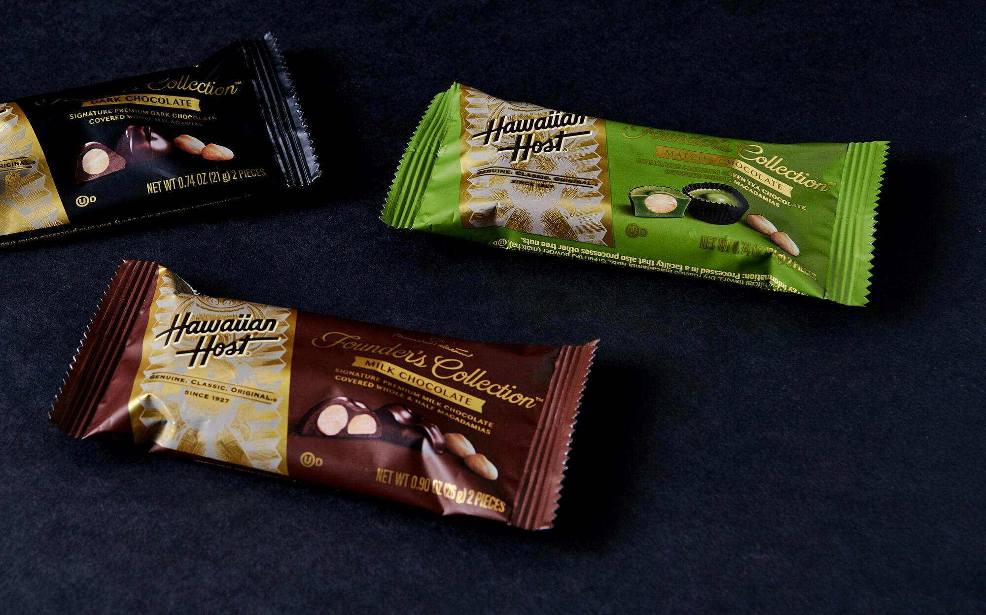 Individually wrapped chocolate macadamia nuts of the dark chocolate flavor, milk chocolate flavor, and matcha flavor.