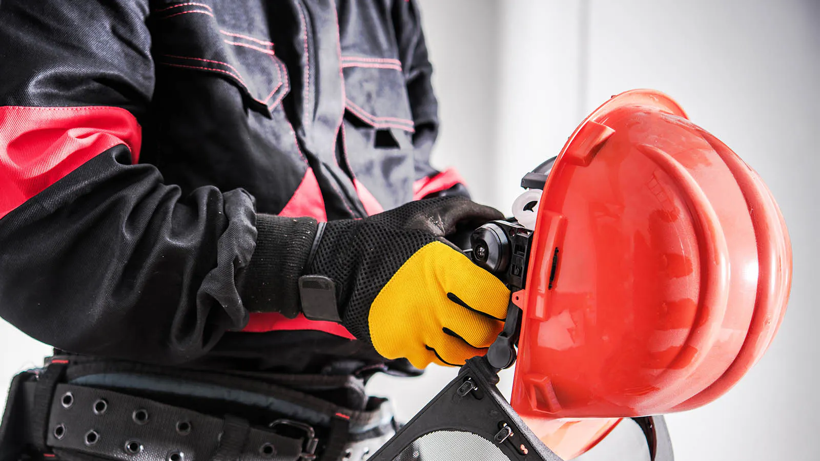 Worker in protective gear putting on gloves next to safety helmet and equipment