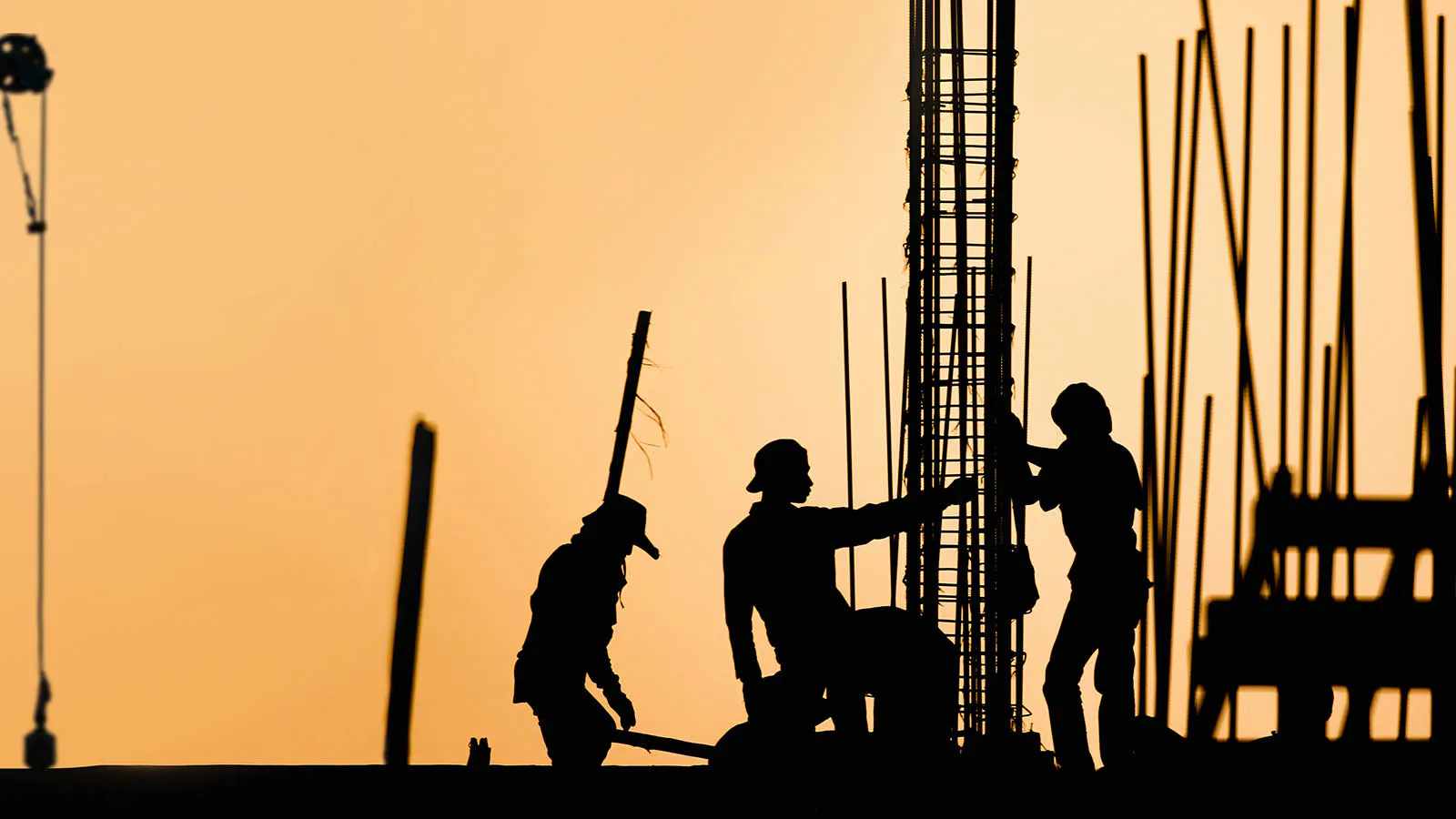 Silhouettes of construction workers on a job site at sunset