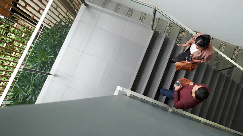 Colleagues with coffee walking up office stairs, seen from above