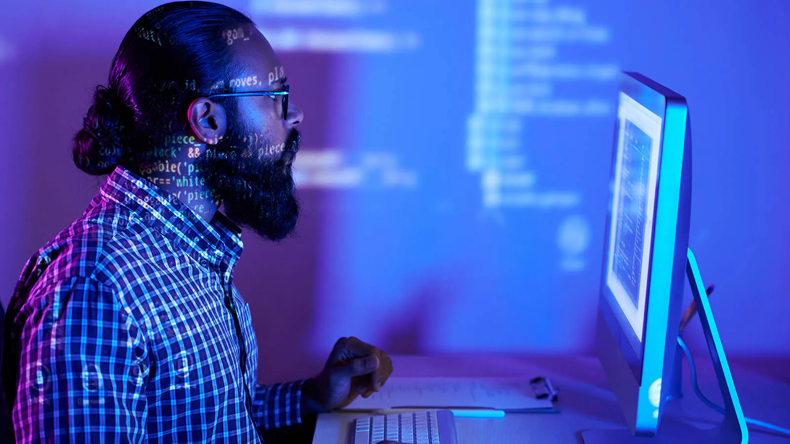 Developer working at a glowing computer screen in a dark office