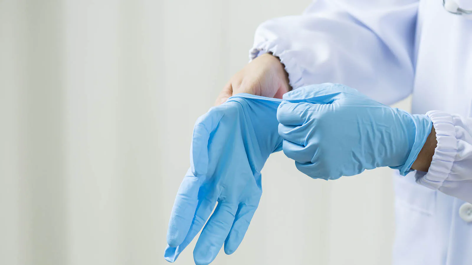 Healthcare worker putting on disposable medical gloves