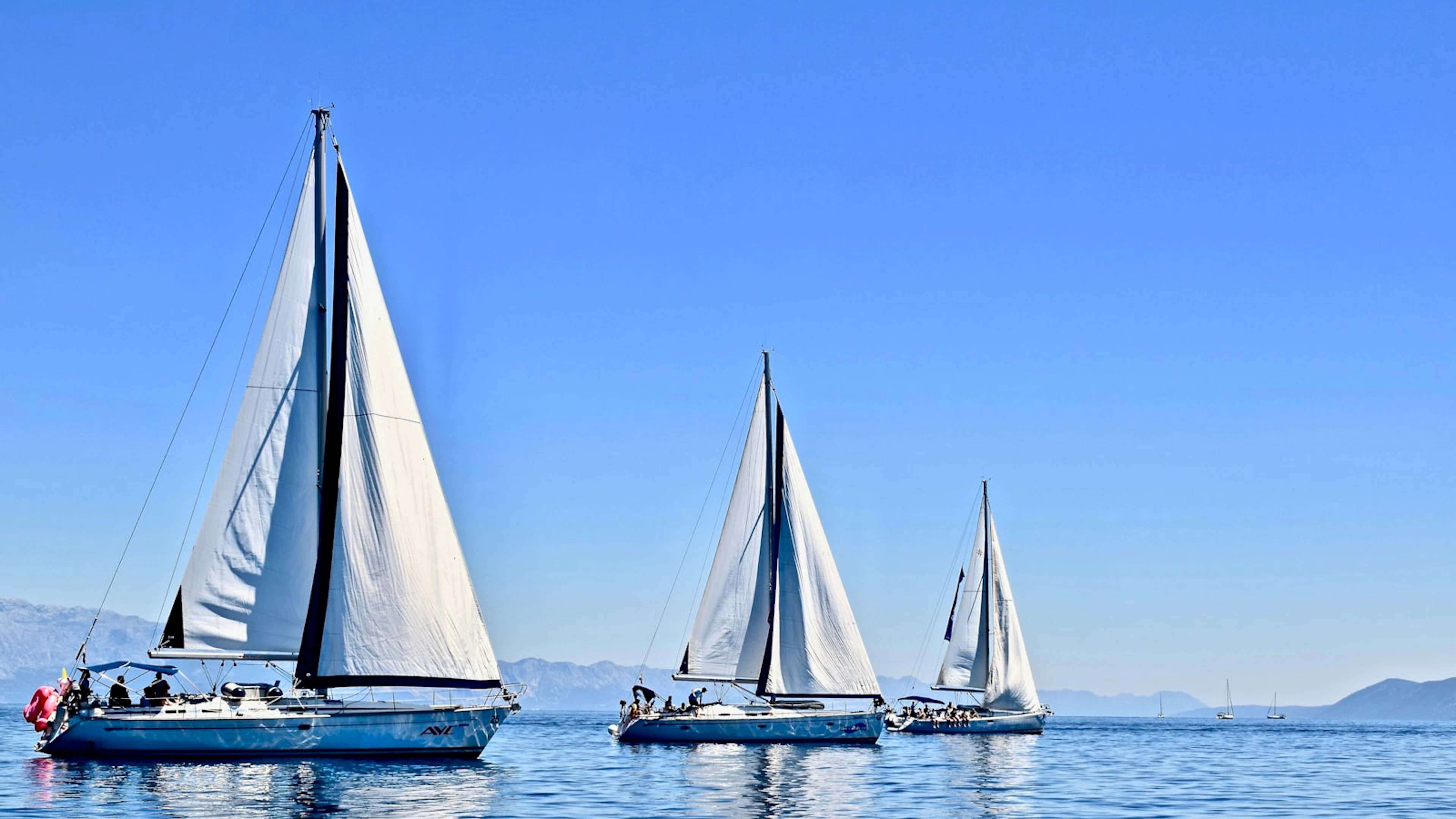 Three sailboats sailing on open Adriatic water